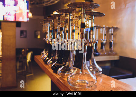 Group of eastern hookahs with black pipes on table in cafe. Shisha smoking concept. Stock Photo