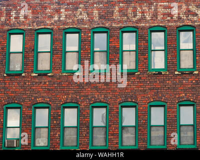 Windows at a old brick auto parts warehouse with seat covers painted sign. Stock Photo