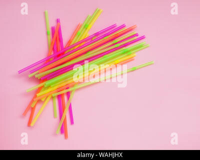 Heap of multicolored plastic cocktail tubes on a pastel pink background. Drinking straws of bright neon colors. Flat lay. Top view. Stock Photo