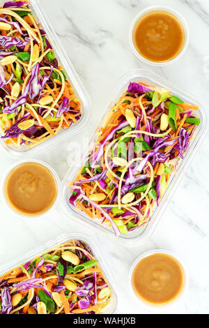 Fresh homemade Thai noodle salad with peanut sauce in meal prep containers for take out lunch.  On marble background in flat lay composition. Stock Photo