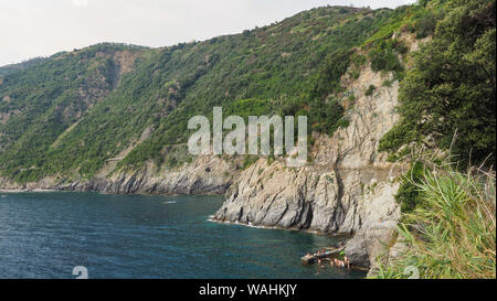 Amazing seashore near the Manarola town. The footpath is curved on steep slopes of hill. Famous Italian National park Cinque Terre. Liguria, Italy. Stock Photo