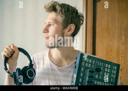 portrait of young bearded man sound producer holding midi controller and headphones f Stock Photo