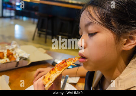 Beautiful Asian boy eating pizza in the restaurant. Stock Photo