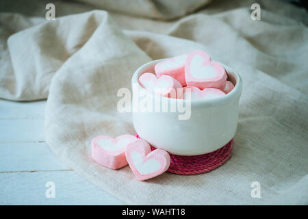 Heart shape marshmallows in white mug on wood background, sweet and  love concept. Stock Photo