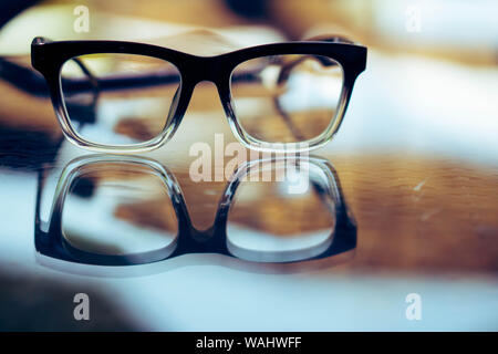 Eye glasses on wood table with  reflection Stock Photo