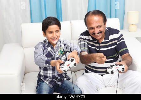 Indian old man with his grandson playing video game at home Stock Photo