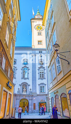 SALZBURG, AUSTRIA - FEBRUARY 27, 2019: The magnificent facade of Altes Rathaus (Old town hall) with high clock tower hidden in narrow medieval streets