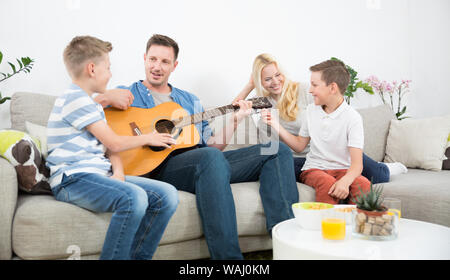 Happy caucasian family smiling, playing guitar and singing songs together at cosy modern home Stock Photo