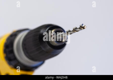 Close up of a masonry drill bit in the chuck of a battery-powered yellow drill Stock Photo