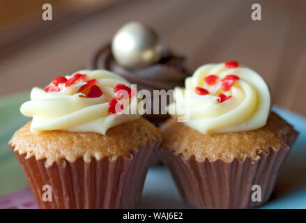 Three cupcakes on the plate on a wooden table indoor Stock Photo