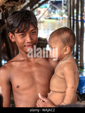 Kompong Pluk (Phluk), Cambodia. Young man holding his infant son. This is a cluster of three villages made of stilt houses within the floodplain of the Tonle Sap River. (Editorial Use Only) Stock Photo