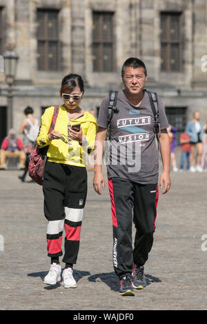Asian tourists on Dam Square. Many popular tourist cities are seriously trying to tackle the mass tourism wave, Amsterdam is a forerunner among them. Stock Photo