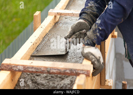 Worker levels concrete in formwork using a trowel Stock Photo