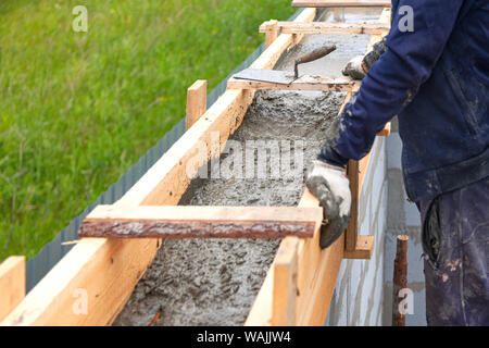 Worker levels concrete in formwork using a trowel Stock Photo