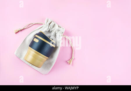 Reusable coffee cup with it's cotton bag on pink background. Zero waste concept. Stock Photo