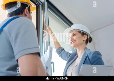 Architect and construction worker checking windows on site Stock Photo