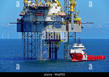 Detail of Prospector 1 drilling platform rig and support ship VOS Precious drilling in North sea with wind turbines in the background Stock Photo