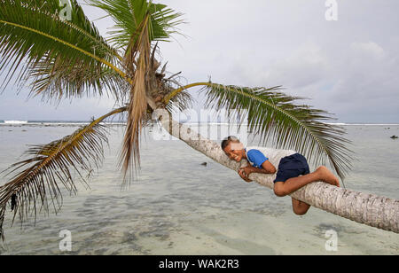 Kosrae, Micronesia (FSM). Local boy playing on palm tree on beach (Editorial Use Only) Stock Photo