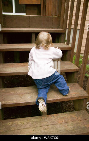 Issaquah, Washington State, USA. 15 month old toddler climbing outside wooden steps. (MR,PR) Stock Photo
