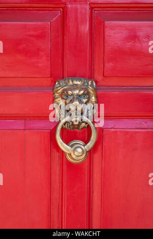 Brass Lions head door knocker on a red wooden door in the ancient Anglo Saxon town of Winchcombe, Cotswolds, Gloucestershire, England Stock Photo