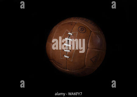 Antique leather football soccer ball against a black background Stock Photo
