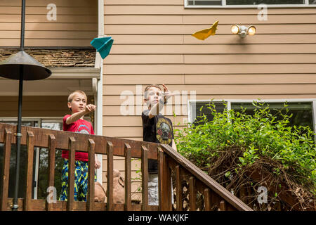 Issaquah, Washington State, USA. 10 and 14 year old boys throwing paper airplanes from a deck. (MR, PR) Stock Photo