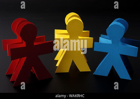 Red yellow and blue paper men isolated on black background Stock Photo