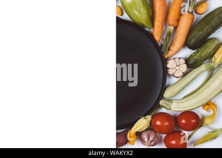 Creative layout made of vegetables. Food concept. Tomatoes, onion, cucumber, carrot, garlic, zucchini and black plate on white background. Flat lay, t Stock Photo