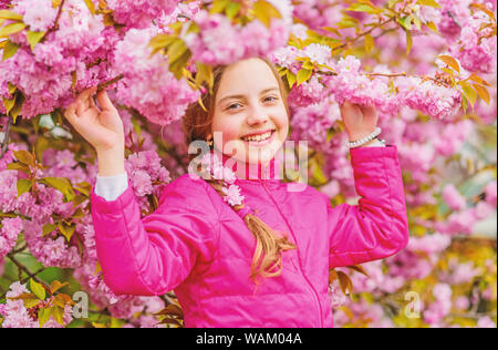 Pink is my favorite. Little girl enjoy spring. Kid on pink flowers of sakura tree background. Kid enjoying pink cherry blossom. Tender bloom. Pink is the most girlish color. Bright and vibrant. Stock Photo