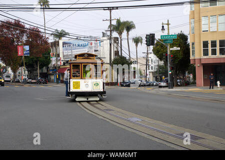 SAN FRANCISCO, CALIFORNIA, UNITED STATES - NOV 25th, 2018: Passengers enjoy a ride in a cable car and crossing street Columbus and Chestnut. It is the Stock Photo