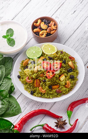 Palak Paneer Biryani and Raita at white wooden background with decor. Palak Paneer Biryani is vegetarian indian cuisine dish with spinach, paneer , ba Stock Photo