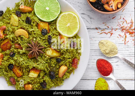 Palak Paneer Biryani and Raita at white wooden background with decor. Palak Paneer Biryani is vegetarian indian cuisine dish with spinach, paneer chee Stock Photo