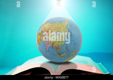 Fluorescent lightbulb over a globe and book Stock Photo