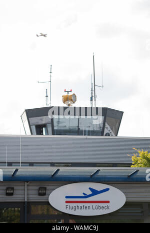 21 August 2019, Schleswig-Holstein, Lübeck: A small airplane flies past the tower of Lübeck airport. The Flensburg tour operator Neubauer Touristik has announced two flights at a press conference on the reopening of the airport for holiday and charter traffic from 2020. The two charter flights are to be launched by tour operators in the spring of next year. Four years after the last scheduled flight of the Hungarian low-cost airline Wizz Air, passenger planes are to take off and land at Lübeck Airport again from 2020. Photo: Rainer Jensen/dpa Stock Photo