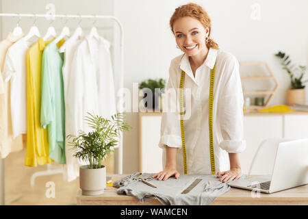 Successful fashion designer. Happy woman standing in workshop Stock Photo