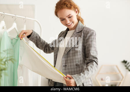Tailor woman measuring shirt sleeve using tape meter Stock Photo