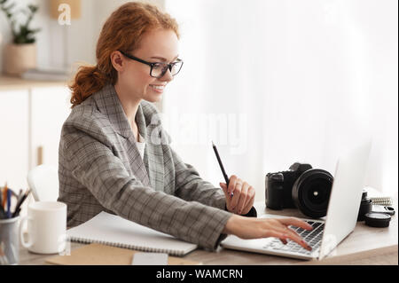 Photographer off loading files on laptop in office Stock Photo