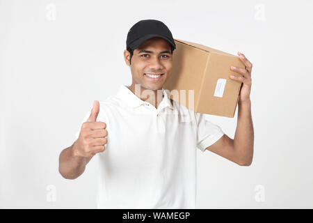 Delivery man holding parcel and showing thumbs up sign Stock Photo