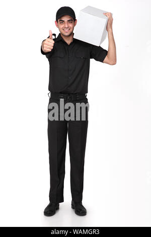 Delivery man standing with parcel and showing thumbs up sign Stock Photo