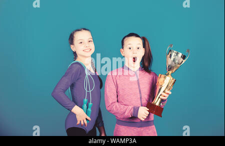 Deserved award. Sport achievement. Girls athletic kids celebrate victory. Athletic girls with golden goblet. Win championship. Our team first place. Children gymnasts athletic kids happy champions. Stock Photo