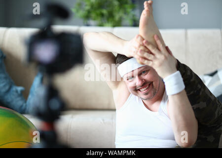 Smiling Man Recording on Camera Leg Stretching Stock Photo