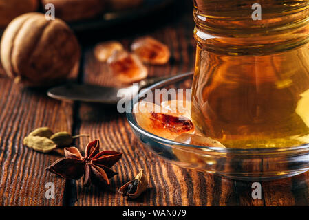 Spiced tea with star anise, cardamom and dried lime in oriental glass over wooden surface Stock Photo