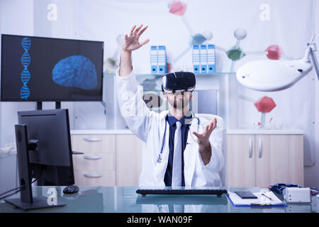Young male doctor conducting medical procedure wearing virtual reality headset. New technology in medicine Stock Photo