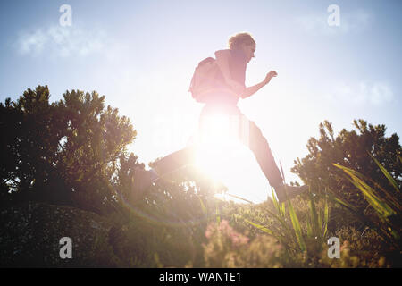 Male hiker running while hiking on sunny day Stock Photo