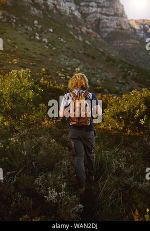 Man with backpack walking on mountain trail Stock Photo