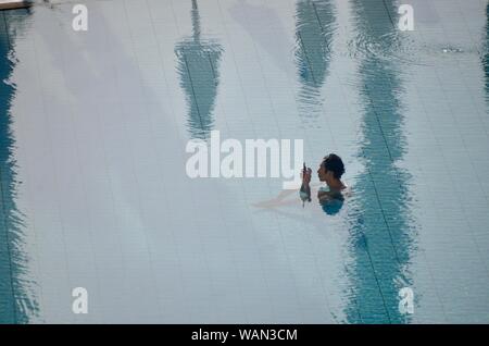 a japanese tourist using his mobile phone in a hilton swimming pool malta Stock Photo