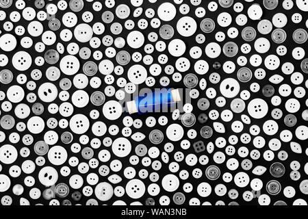 background - different light buttons and reel of blue thread with needle on a dark surface Stock Photo