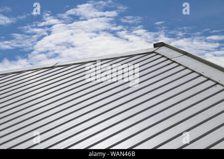 Metal sheet roof and slope with clouds and blue sky background. Stock Photo