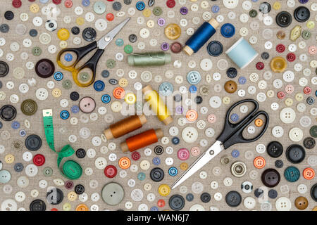 background - multicolored buttons and accessories for sewing lie on a rough fabric Stock Photo