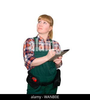 young woman in a work overalls make sketches or enters data with a stylus in the tablet, looking up, isolated on white background Stock Photo